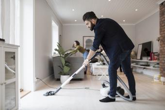 Man vacuuming floor while woman is cleaning