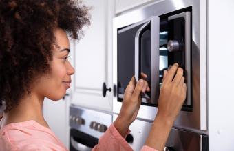 Woman Adjusting Temperature Of Microwave Oven