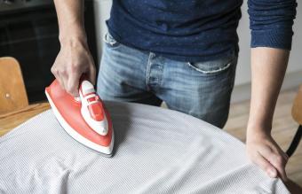 man ironing shirt on table