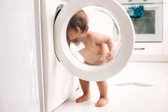 baby standing near washer