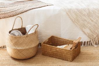 Straw basket on wicker carpet near bed