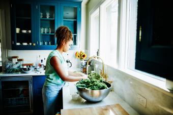 Woman washing organic kale in kitchen sink