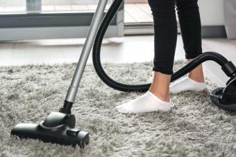 Woman Using Vacuum Cleaner On Carpet