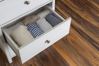 White wooden drawer and rolled shirts in it against wooden floor at home