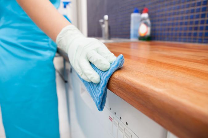 hands with gloves wiping kitchen counter