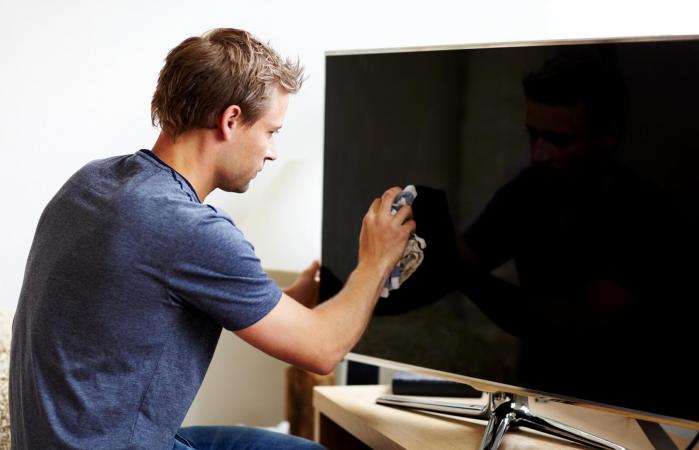 Man cleaning the screen of his smart TV