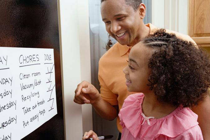 Father and daughter looking at chores chart