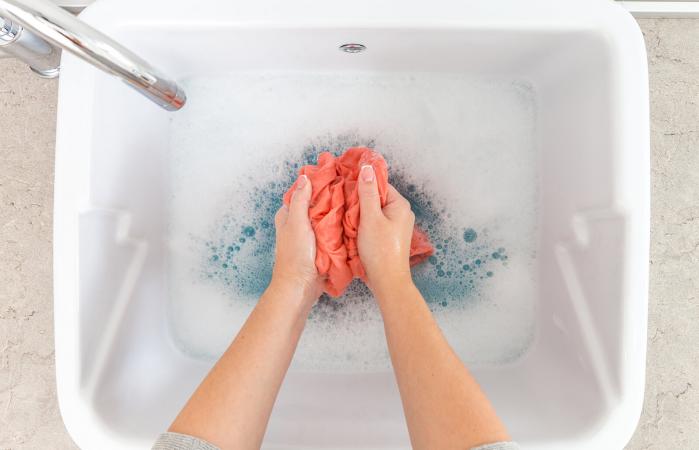 Female hands washing color clothes in sink