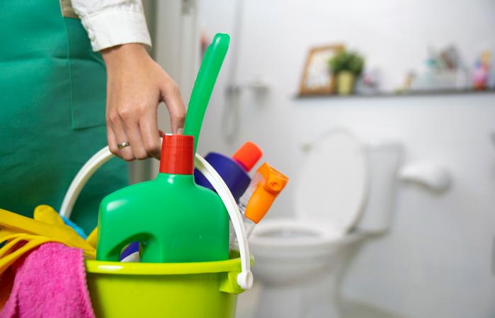 woman holding a blue bucket full of chemicals