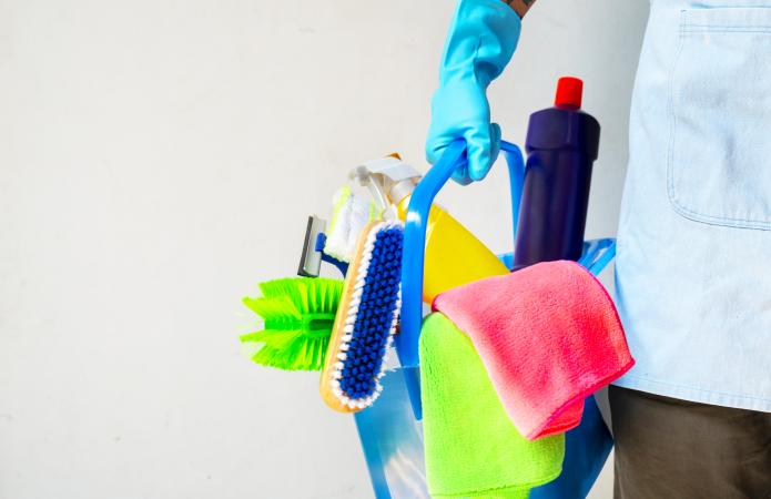 Man holding mop and plastic bucket with brushes, gloves and detergents