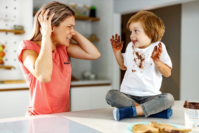 Frustrated mother looking at her messy son in the kitchen