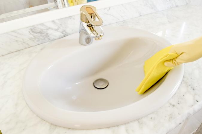 Cleaning porcelain sink with yellow gloves