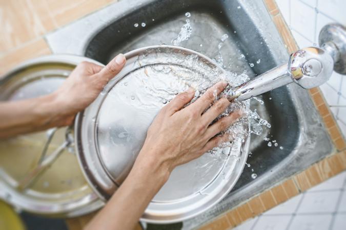 Woman Washing Dishes In Kitchen Sink