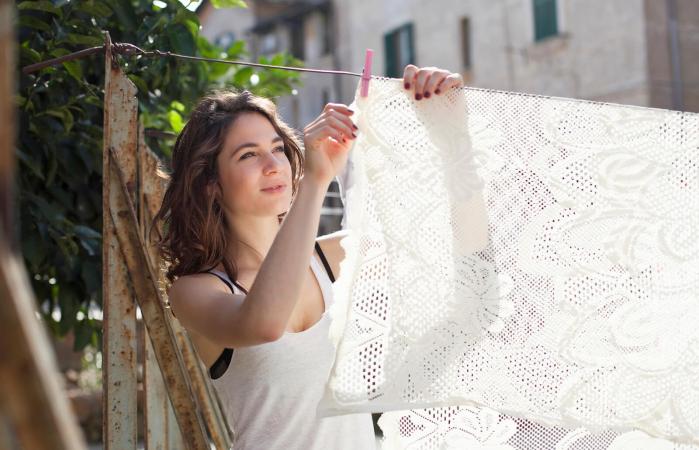 woman hanging table cloth on clothesline