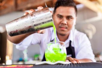 Male Bartender Preparing Green Cocktail In Bar