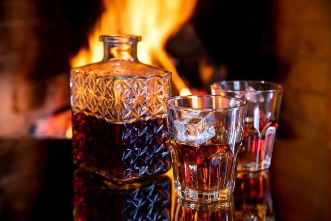 Two glasses and a of whiskey near the fireplace