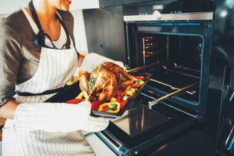 woman taking the turkey out of the oven