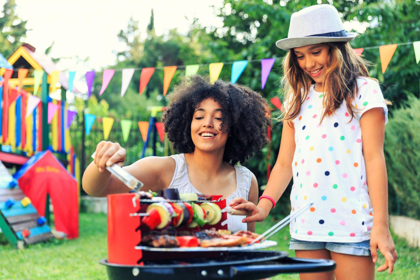 Mother and daughter having fun and preparing barbecue at backyard