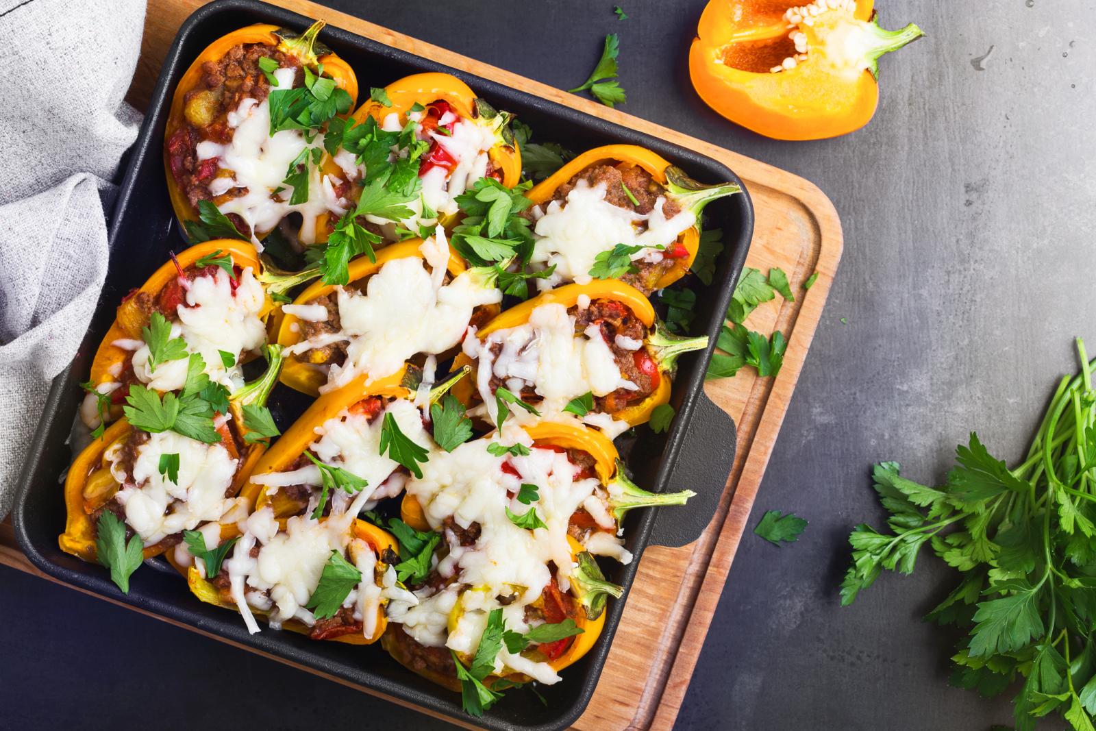 Overhead view of stuffed bell peppers with minced meat and vegetables served in cast iron skillet