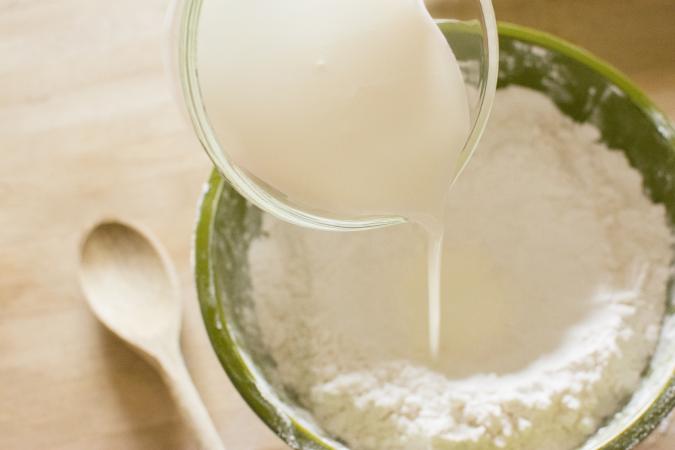 Adding milk to bowl of flour