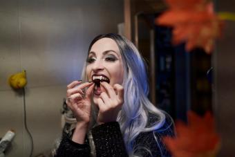 Woman with Halloween costume puts on false vampire teeth