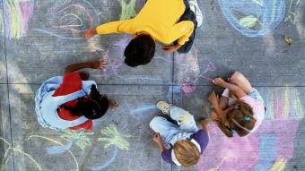 Four children drawing with chalk on pavement