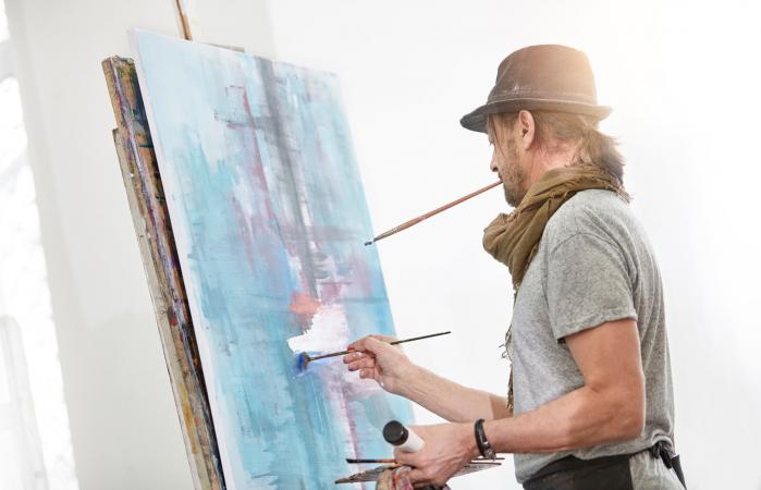 Male artist painting at easel