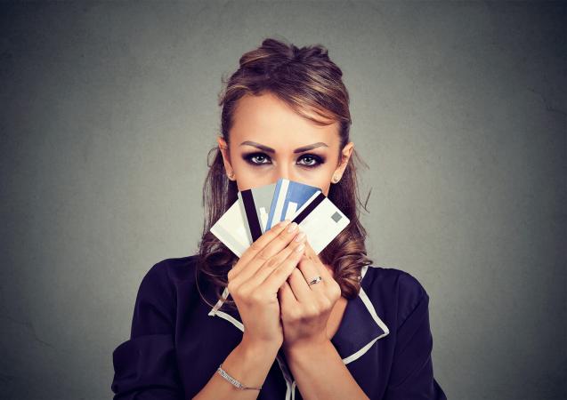 Woman hiding face behind many credit cards