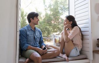 Smiling young couple sitting on windowsill