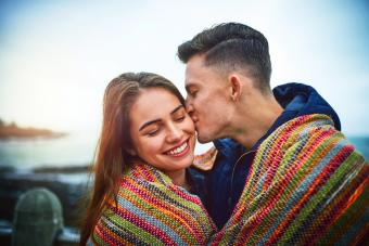 Happy young couple covering themselves with a blanket outdoors