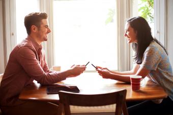 Man and woman on a date using smart phones at table