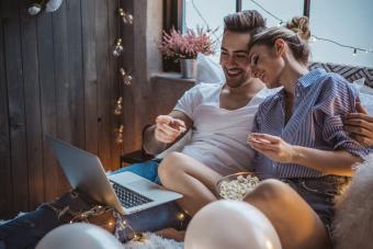 Couple in bed watching movie and eating popcorn