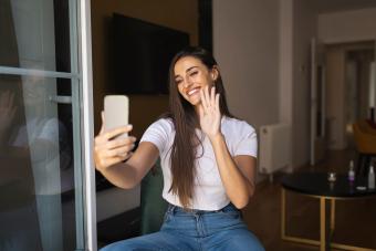 Smiling young woman waving hand during video call 