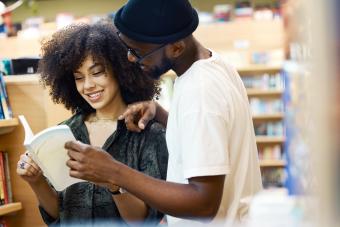 Young couple smiling looking at a book in bookstore