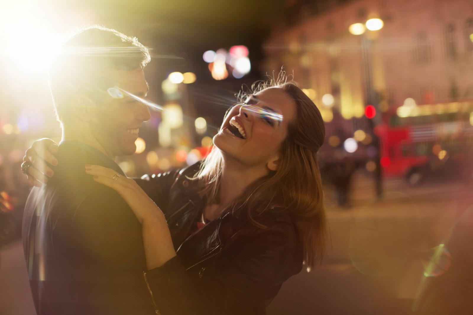 Couple hugging on city street at night