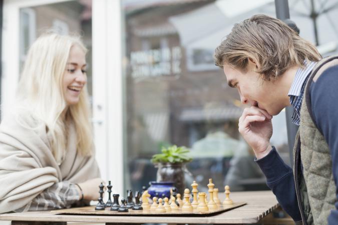 Happy couple playing chess at outdoor cafe