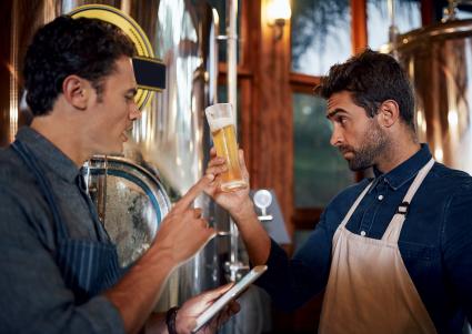 Two men at a brewing inspecting a beer