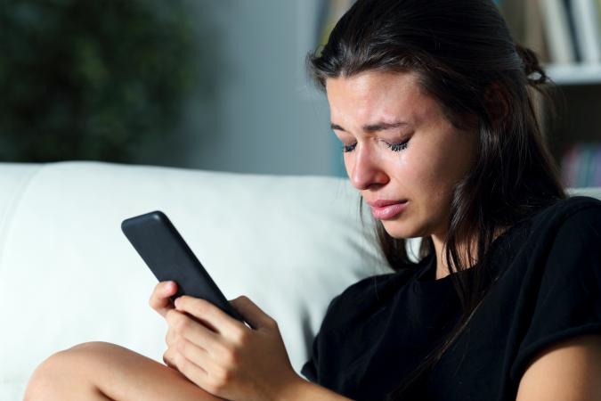 Sad woman crying while looking at phone