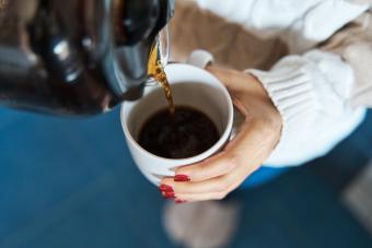 Woman pouring herself hot coffee to a mug