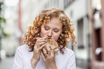 Young woman eating bagel outdoors 