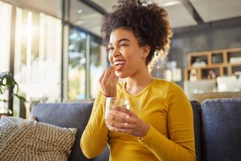 woman taking medication with water at home