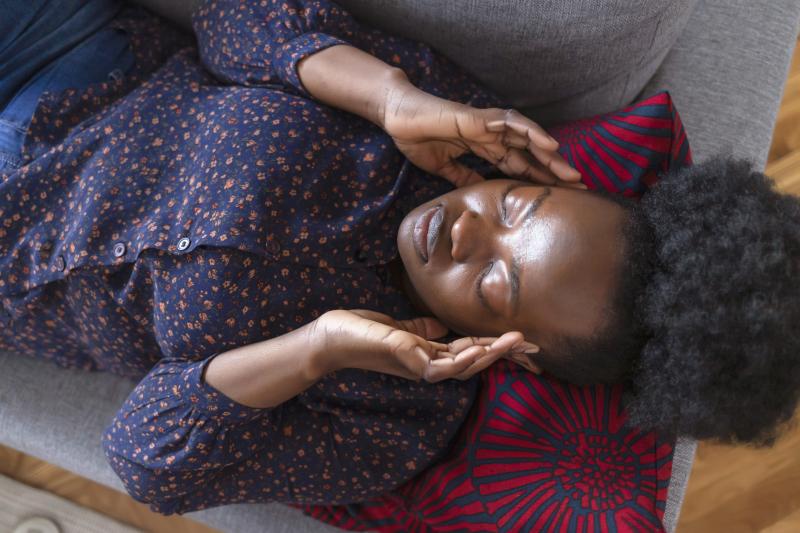 Woman lying on couch feeling strong headache