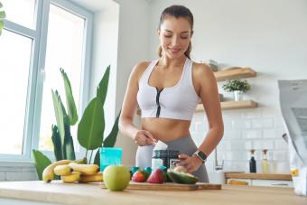 Young woman in sports clothing preparing whey protein shake at home