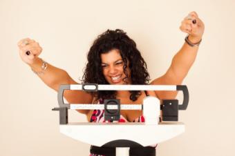 Happy woman celebrating on scales