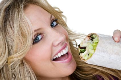Woman eating a healthy wrap.
