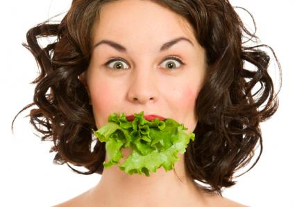 Woman with lettuce in mouth