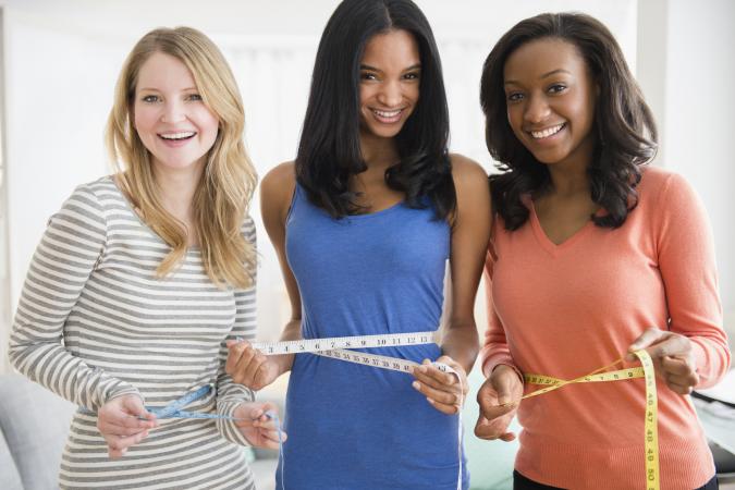 Women measuring their waistlines