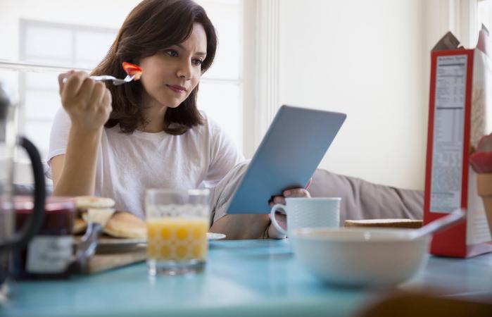 Woman using digital tablet at breakfast table