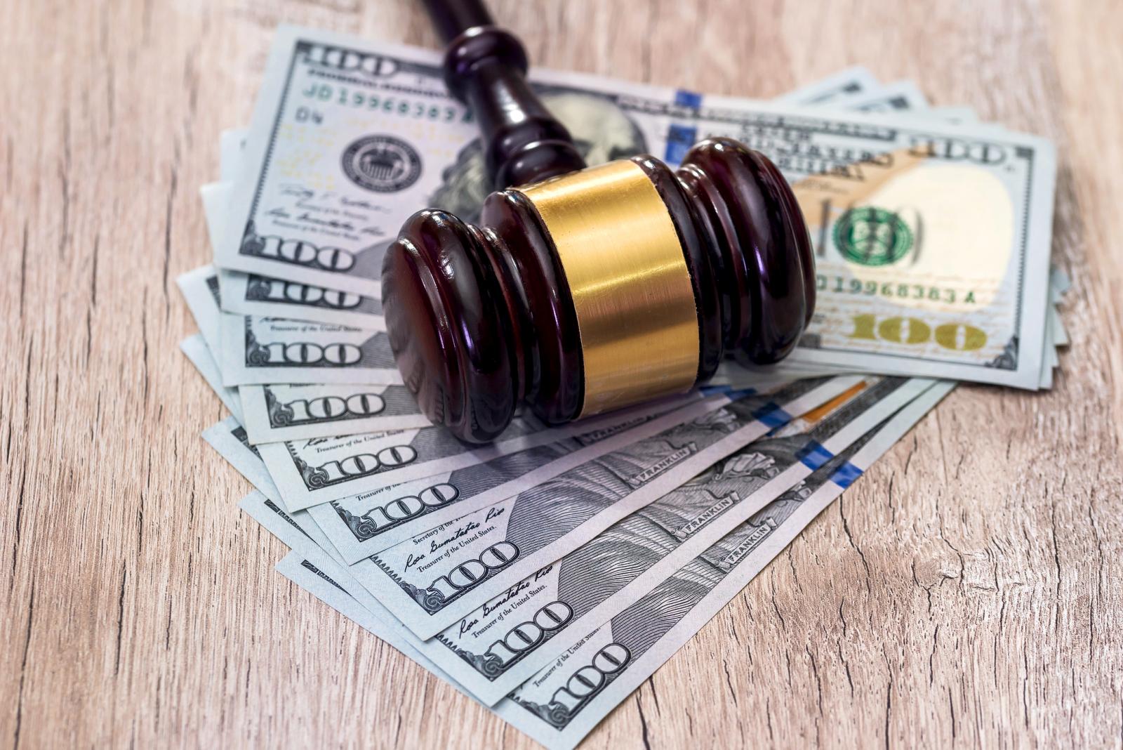 Judge's gavel with American dollars on wooden table