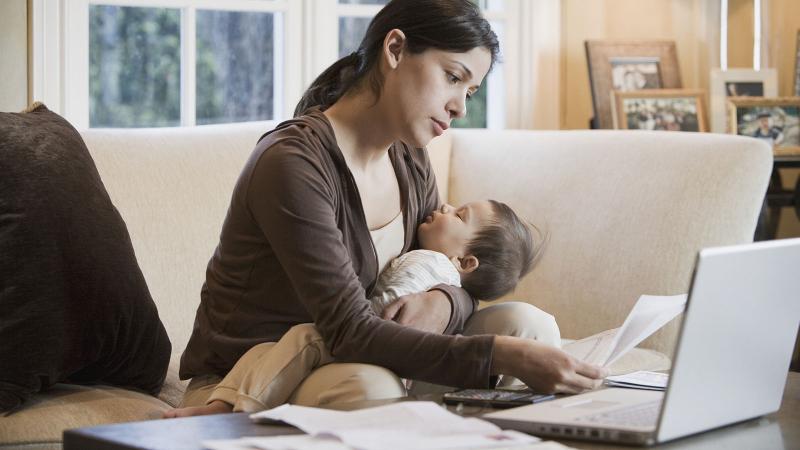 Woman paying bills online while holding baby